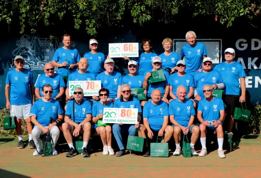 Zawodniczki i zawodnicy Team Seniora Klubu Tenisowego GAT Gdańsk z tablicami 60+, 70+ i 80+ na korcie