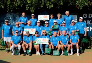 Zawodniczki i zawodnicy Team Seniora Klubu Tenisowego GAT Gdańsk z tablicami 60+, 70+ i 80+ na korcie